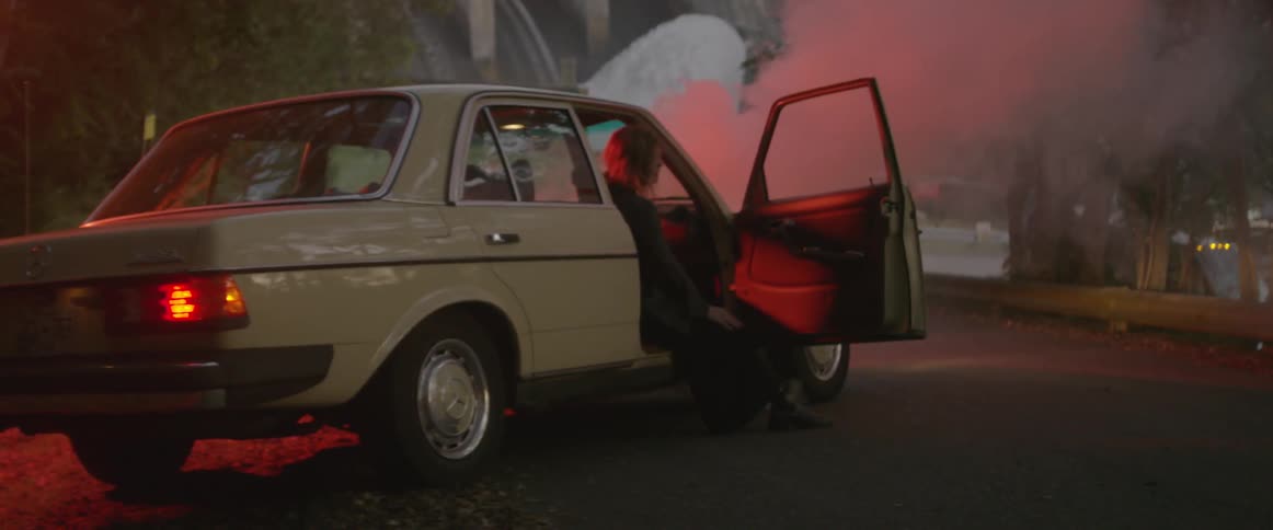 A woman sits in a car with the door open