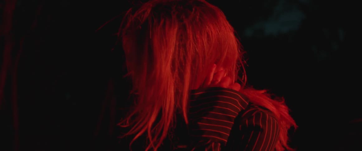 A rubs her hand through her hair outside at night