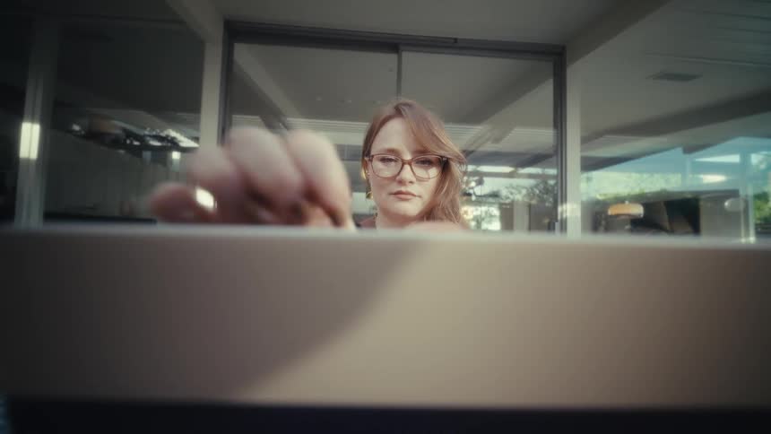 The woman smiles while opening her laptop