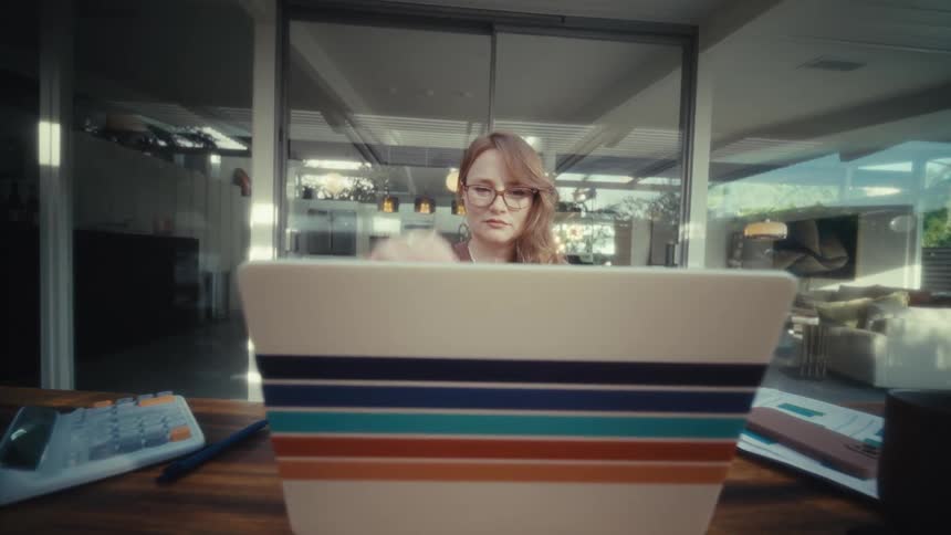 The woman opens her laptop on the large table