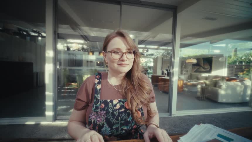 Young woman sits at a table with a laptop computer and smiles as she closes the lid