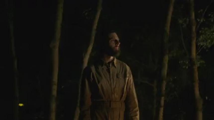 A man stands outside at night in front of flashing lights