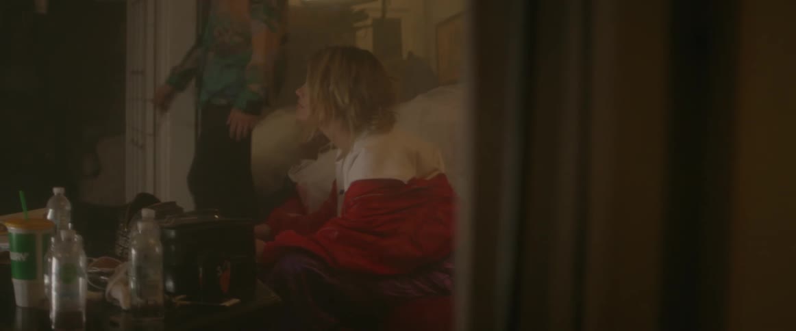 A woman sits on a couch as people walk by