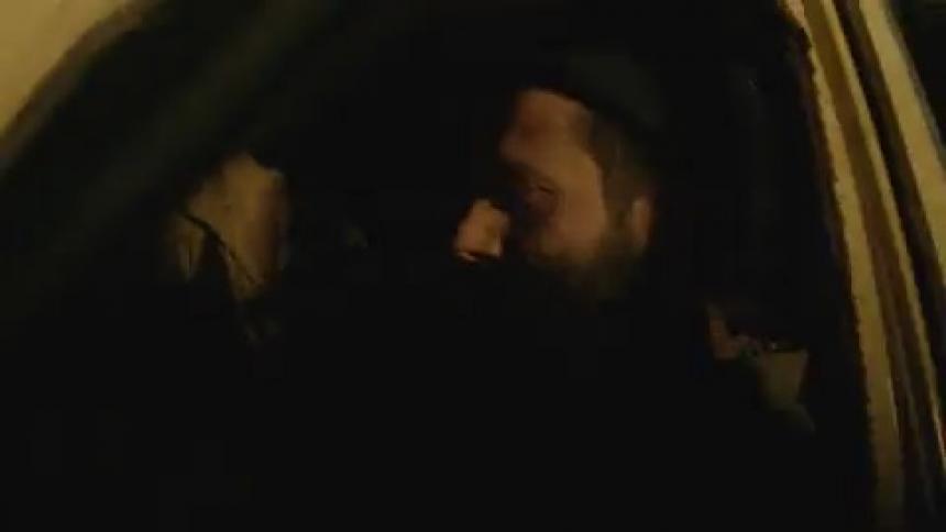 Lights flash on a man sitting in a car in the dark