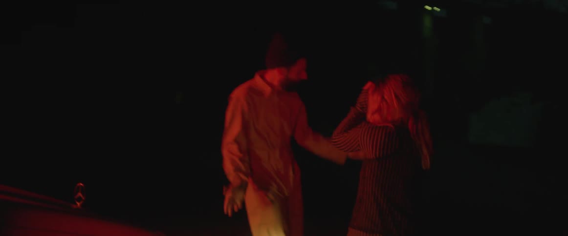 A man and a woman are dancing outdoors at night