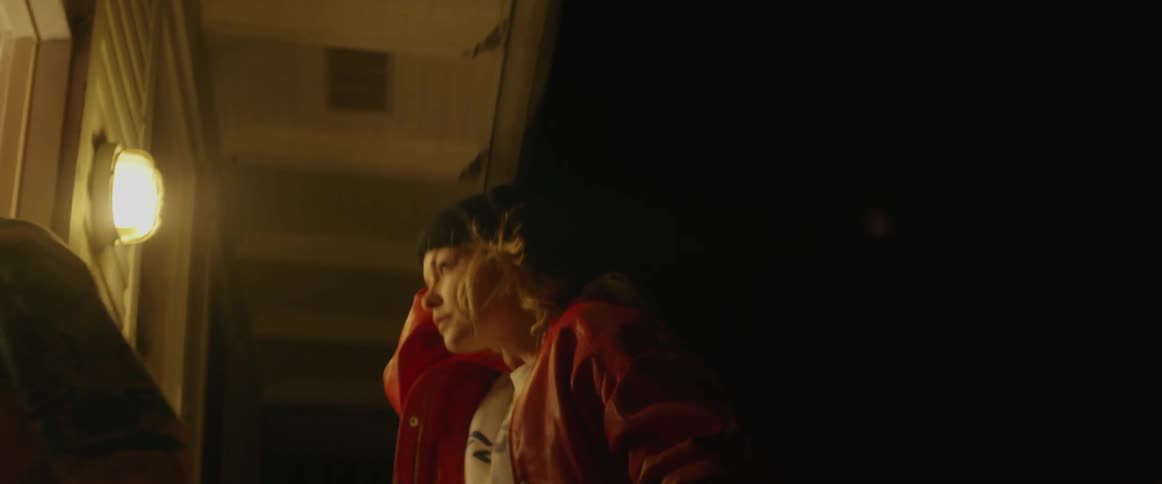 A woman flips up her ski mask before entering a house