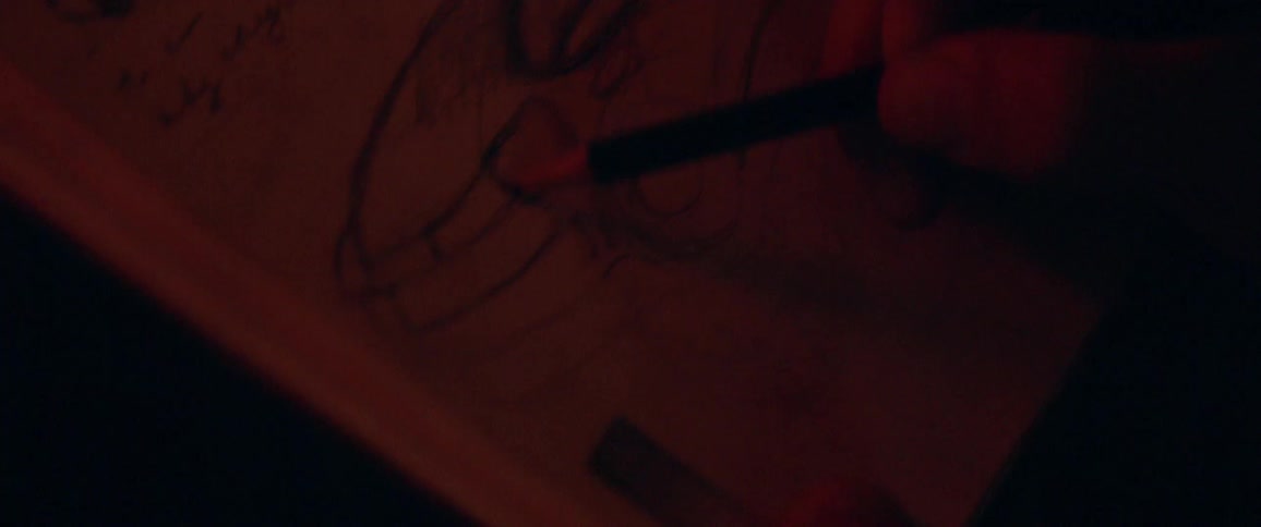 A person sketches with a pencil on a small paper