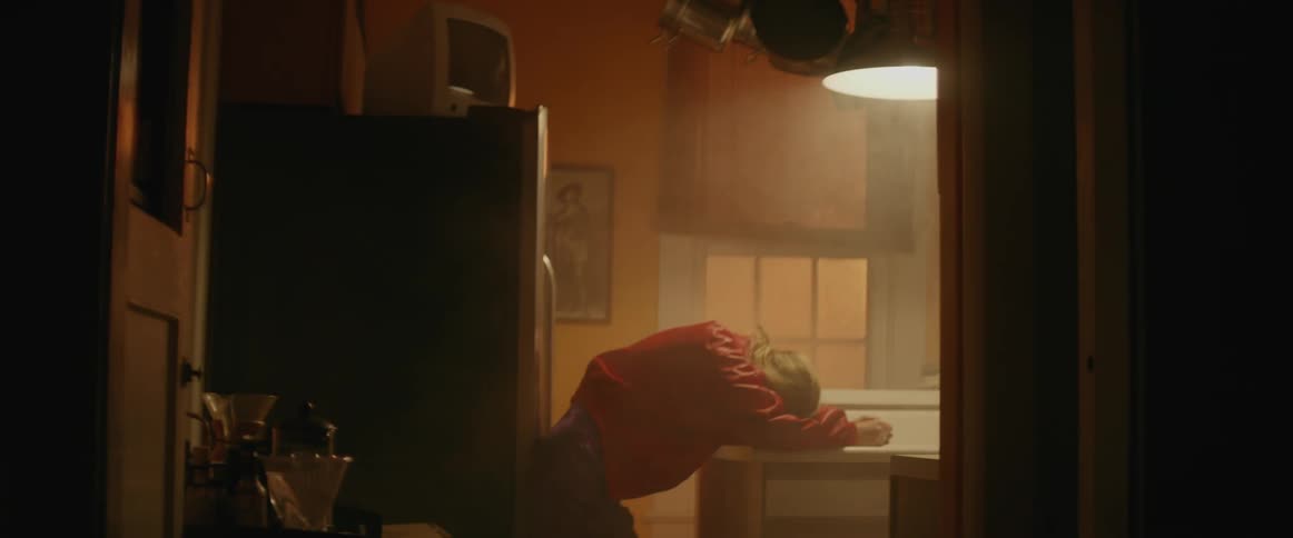 A woman leans over a counter in a kitchen as the light turns on