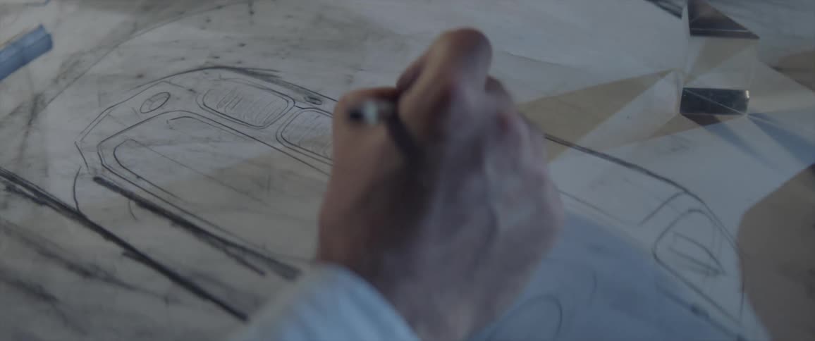 A man sketches a car design in a book