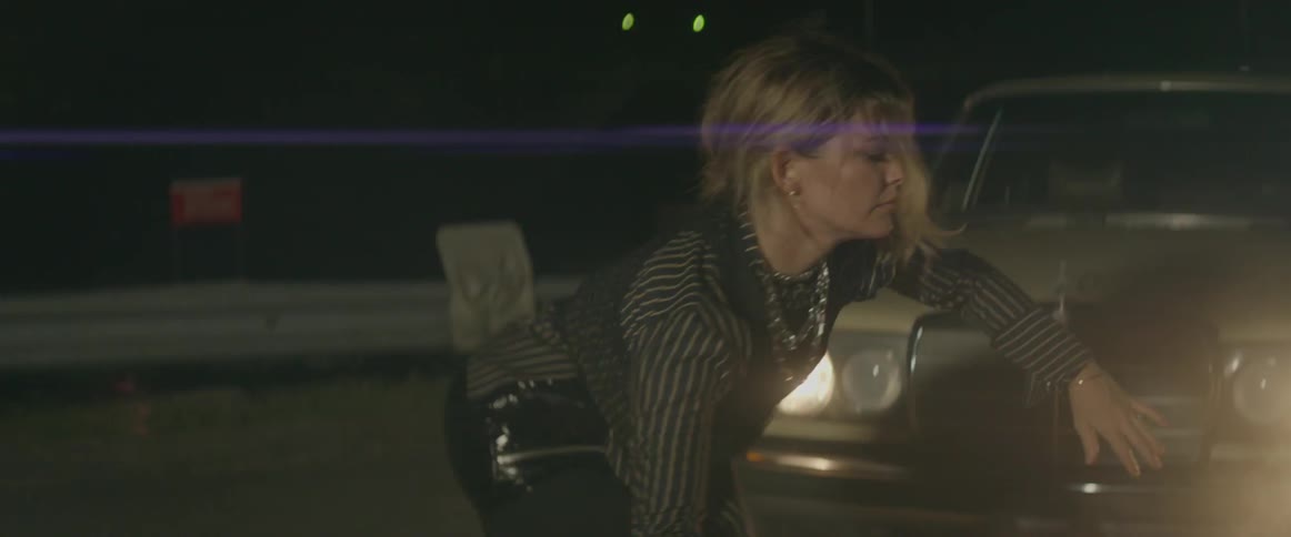Woman dances in a dark room with light shining on and off of her
