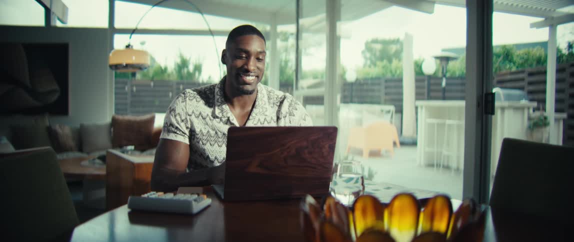 The man waves and talks to his laptop