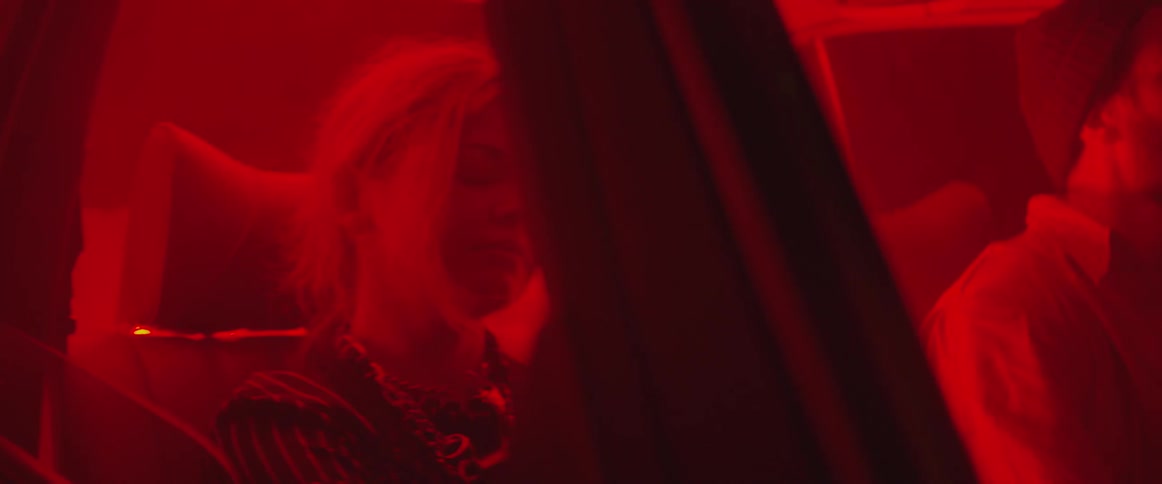 A woman sits inside a car that is glowing red