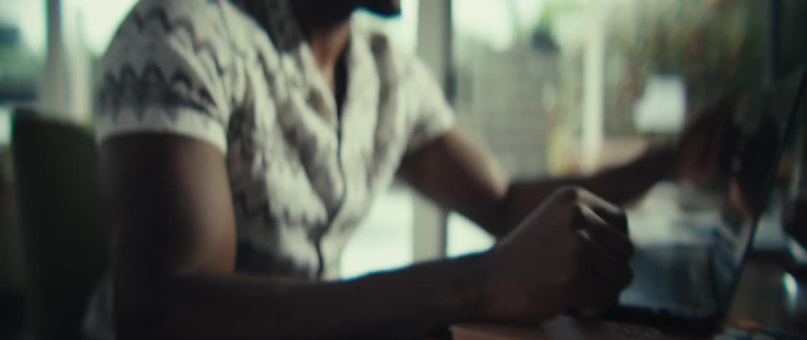 A man sitting at a table uses a calculator and a laptop computer