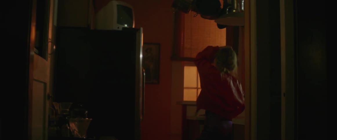 Woman dancing in kitchen while light flashes on and off above her