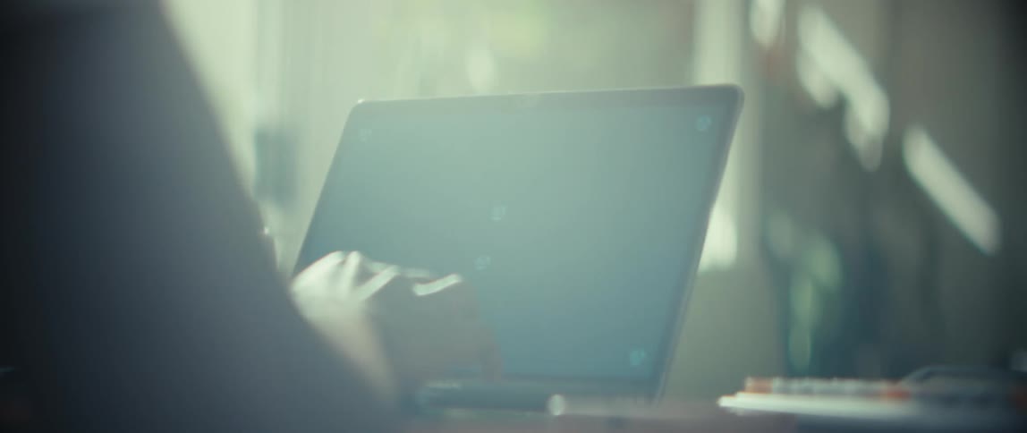 Person typing on laptop with notebook and calculator on the table