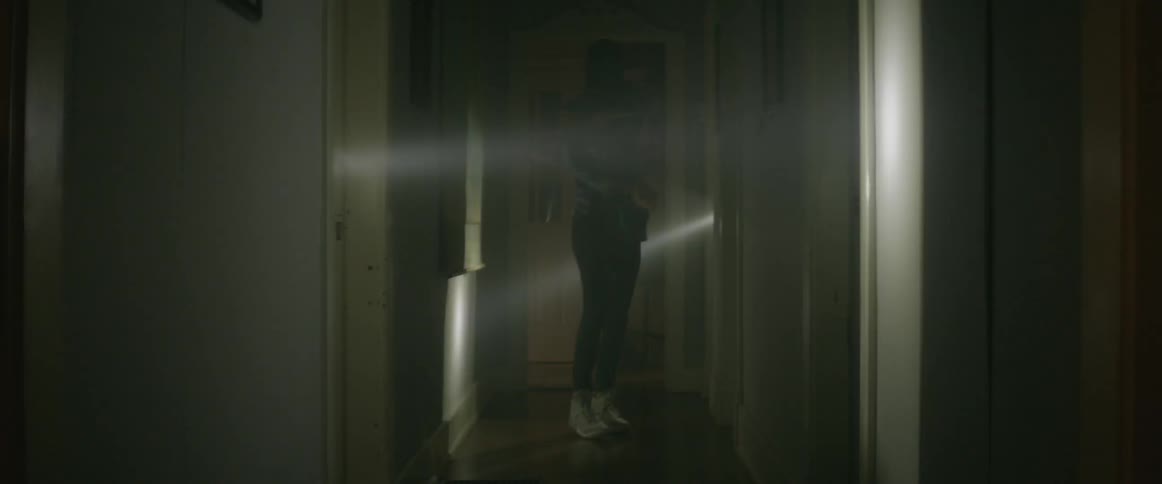 Person dancing in a dark hallway with beams of moving light shining all around