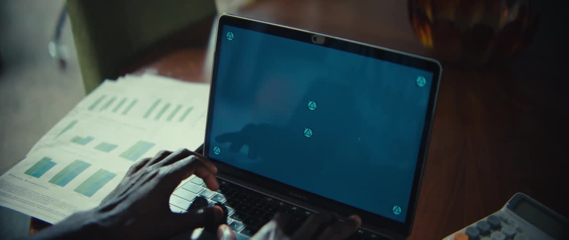 A man sits at a table while typing on the keyboard of his laptop computer
