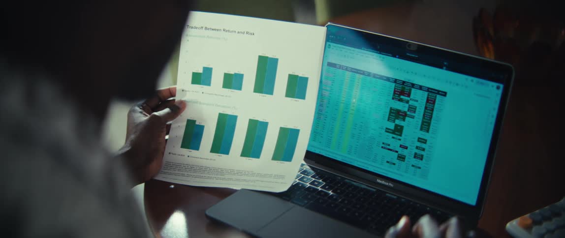 Man sitting at a table in front of a laptop computer comparing a document to the chart