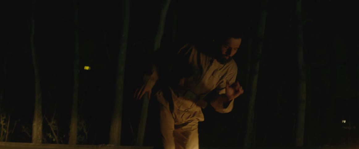 A man dances outside at night with flashing lights