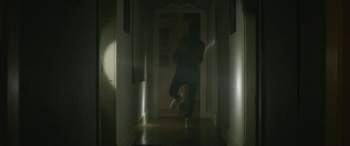 Person dancing in a dark hallway with beams of moving light shining all around