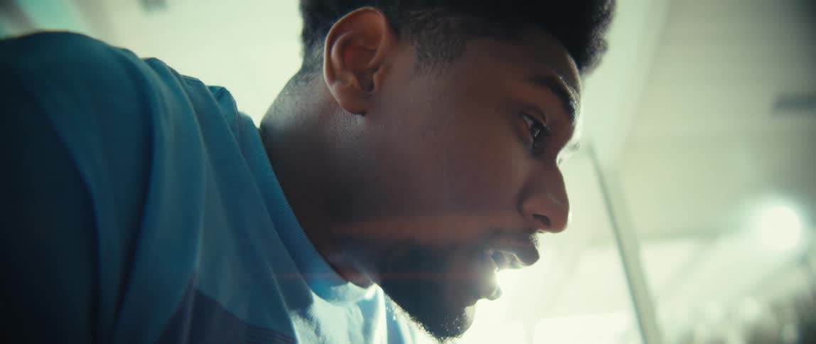 A close up of a black man talking he is smilinh and happy then puts his head down in sadness in a sunlit room