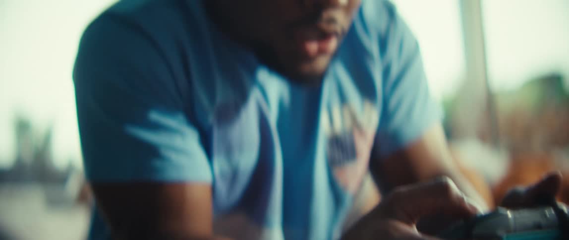 Man sitting on a couch holding a video game controller pushing buttons and turning in excitement