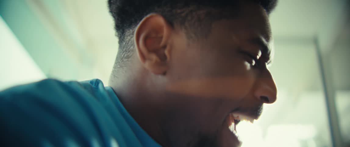 A black man sits in a sunlit room clapping and cheering