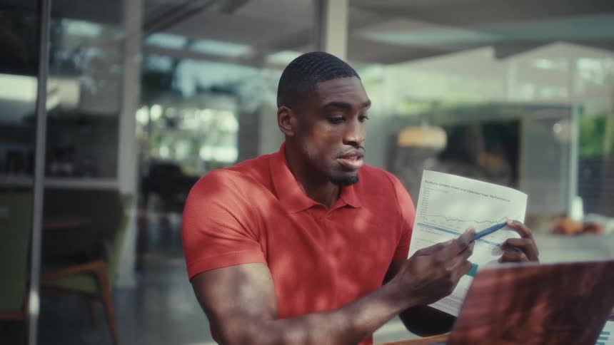 The man talks and points with a pen at a piece of paper