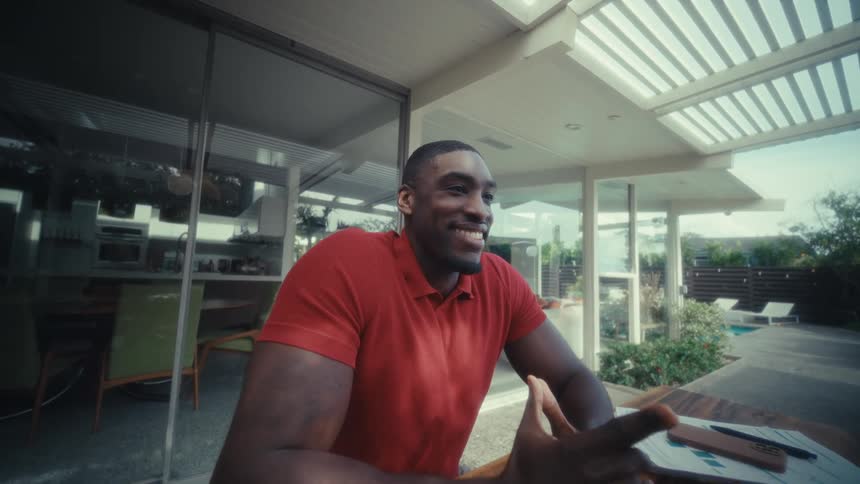 Man sitting at a table on the patio with a calculator and a laptop smiles after closing his laptop