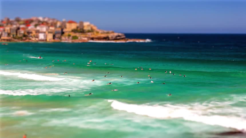 A group of people swim in the ocean near the beach at midday