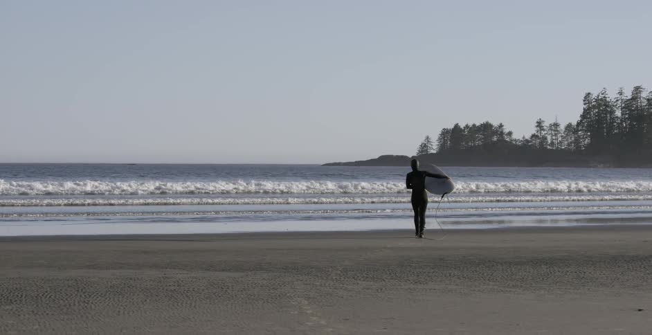 A female surfer is carrying her board as she walks toward the waves