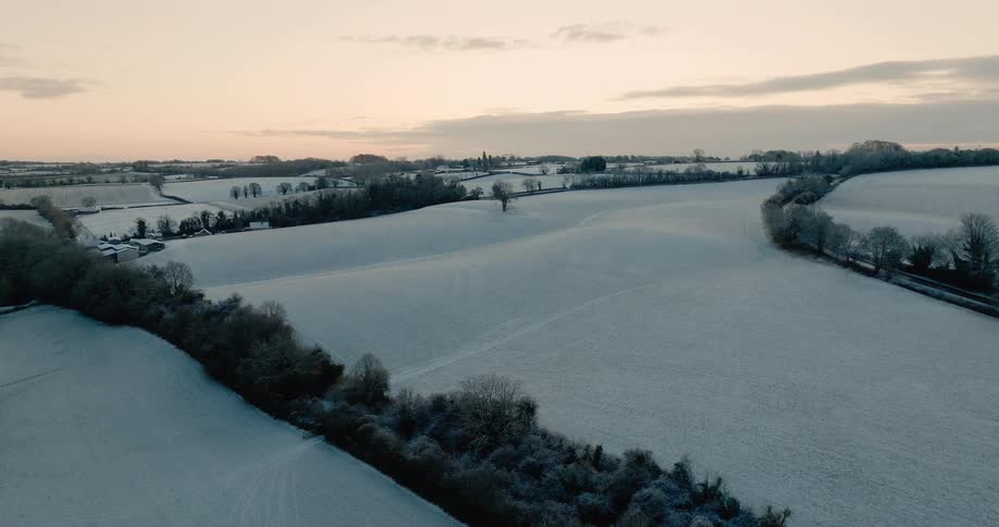 Aerial footage of several snow covered fields in a rural area