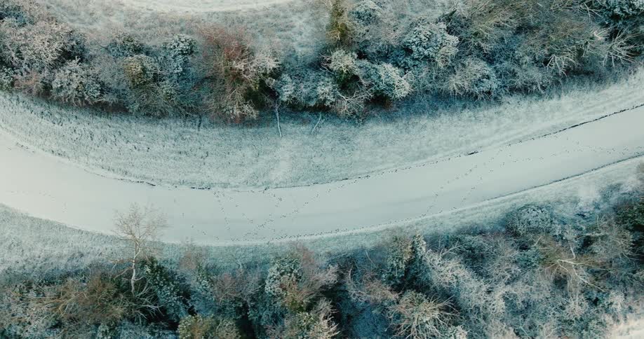 Aerial view moving around a curve on a snow covered forest road