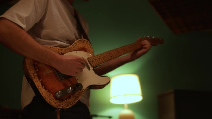 A man playing the guitar in a recording studio