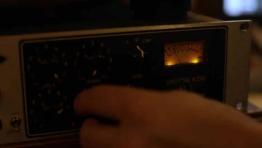 Hand adjusting a knob on a vintage audio equipment indoors