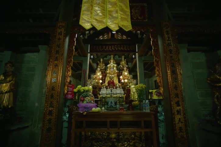 Statues over an altar with candles and banners around indoors