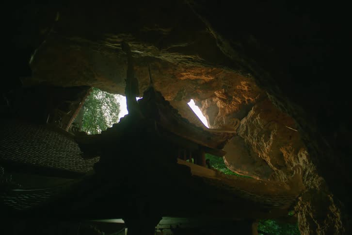 A shrine with asian style design is located in a rocky cave