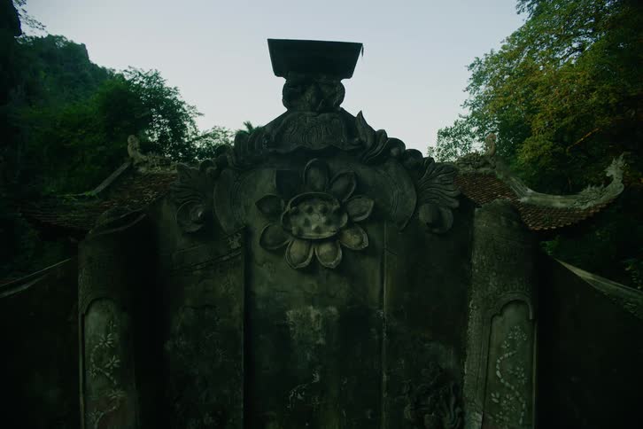 A statue in front of a monk temple in the woods at midday