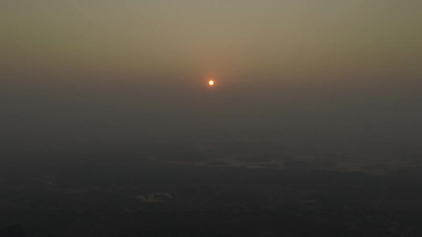 The sun is rising behind the heavy fog