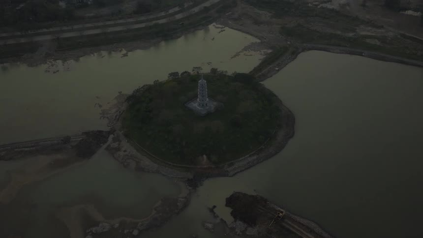 Monument on an island surrounded by dense vegetation outdoors during dusk or dawn