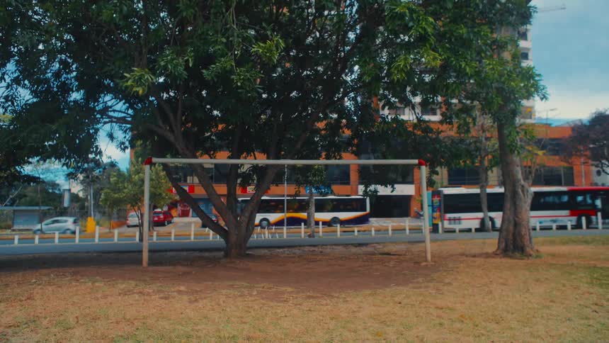 Cars and busses travel on a road by a building and a park