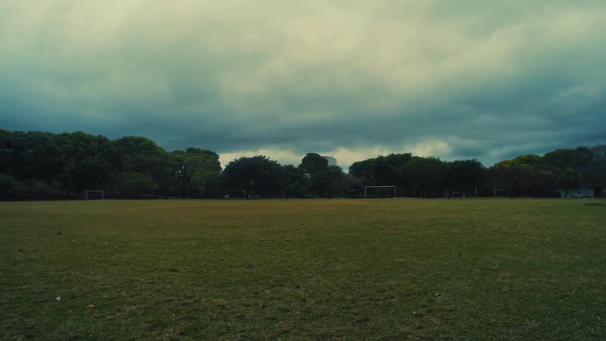 An empty soccer field under dark stormy clouds