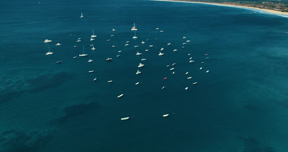 Many boats float offshore in blue waters on a summer day