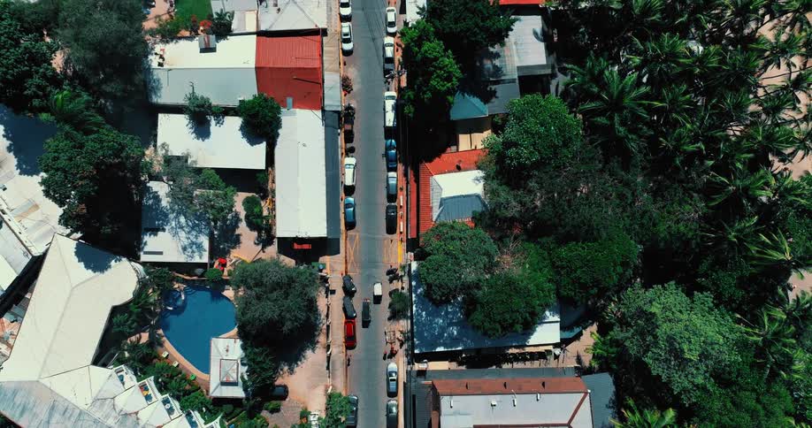 Aerial view of light traffic on a neighborhood street with cars parked on both sides