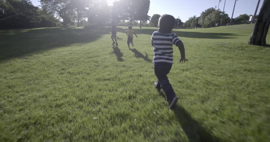 Three children run in a field on a sunny day