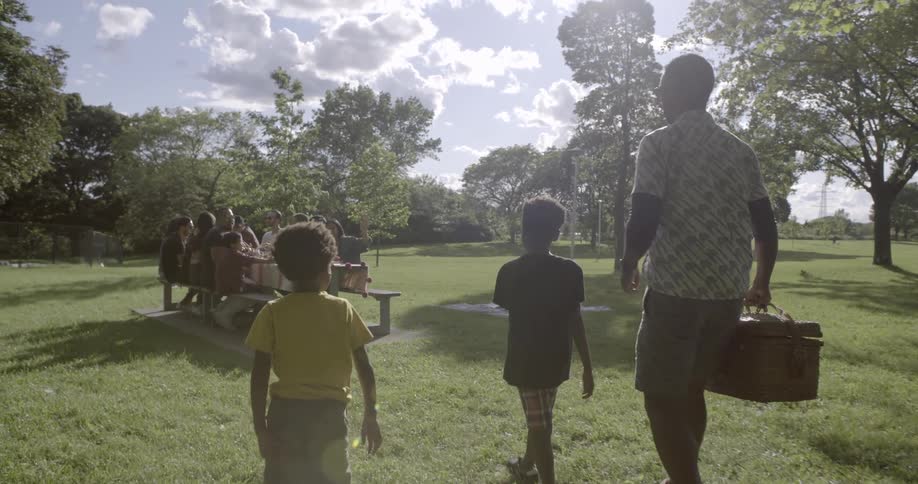 A man and children approach a picnic table full of people