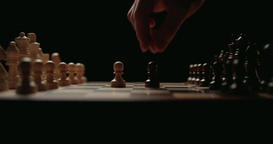 A person slides one of their pawns across the surface of a chessboard