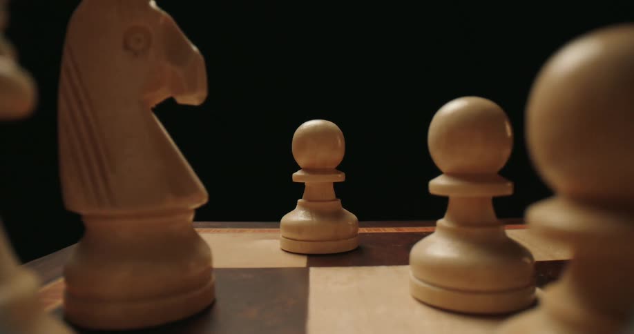 A close up shot of white chess pieces on a chessboard with a dark background