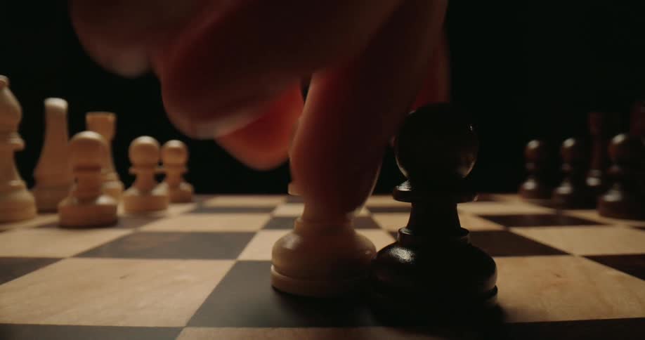 Closeup of a person taking a pawn in a chess game