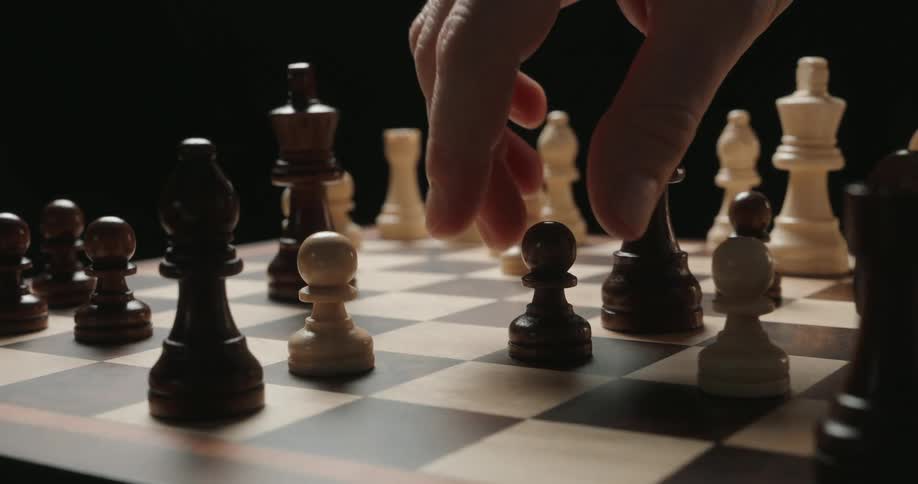 The person slides the chess piece across the board